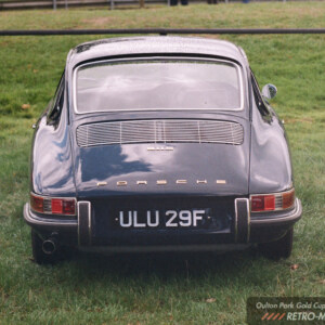 Rear view of a black early Porsche 911 parked on grass at Oulton Park