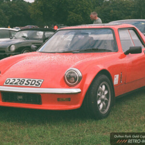 Red GTM sports car parked on wet grass at the 2026 Oulton Park Gold Cup