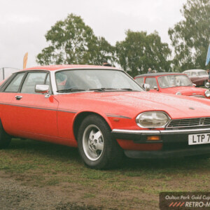Red Jaguar XJ-S parked on wet grass at the 2026 Oulton Park Gold Cup, with Minis behind